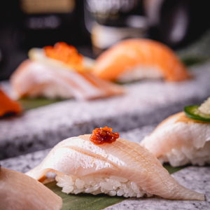 Close-up of fresh nigiri sushi pieces arranged on a stone serving platter.