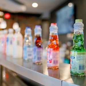 Row of colorful Ramune marble sodas in glass bottles on a restaurant counter.